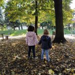 bambine camminano su prato coperto di foglie